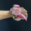 Pink floral wrist corsage with ribbon on a person's wrist
