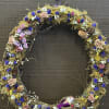 A dried floral wreath with purple, pink, white, and yellow accents.