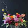 Mixed bouquet of roses, carnations, and orange blooms in a gray vase