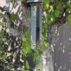 Hanging metal wind chime with butterfly and sunflower designs on a tree