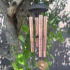 Rose-gold wind chime hanging from a tree branch