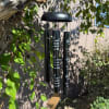 Black memorial wind chime hanging outdoors from a tree