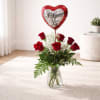 Red roses in a glass vase with a heart balloon reading I Love You