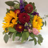 Mixed bouquet with sunflowers, purple blooms, and red dahlias in a glass vase