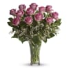 Dozen pink roses with white filler flowers in a clear glass vase