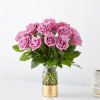 Arrangement of lavender-pink roses in a clear glass vase with a gold metal base