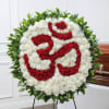 Round white carnation wreath with red Om symbol and a green foliage border on a standing easel