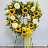 Heart-shaped floral wreath with sunflowers and white roses on a stand