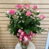 Pink roses arranged in a clear glass vase with a pink ribbon bow