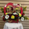 Red basket arrangement with red roses, white daisies, and yellow carnations