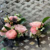 Two small pink rose boutonnieres with black ribbon accents