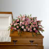 Pink rose and lily casket spray on a wooden coffin