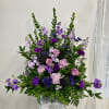 Tall purple and pink floral arrangement in a white pedestal vase
