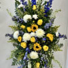 Tall standing floral spray with yellow roses, white mums, and blue delphinium