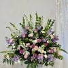 Large pastel floral arrangement in a white pedestal vase
