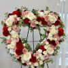 Heart-shaped floral wreath of red, pink, and white roses on a stand