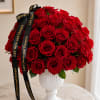Red rose bouquet in a white pedestal vase with black ribbon