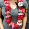 Woman wearing a lei of red and pink carnations with a black ribbon bow