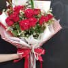 Bouquet of red roses wrapped in striped paper with a red ribbon