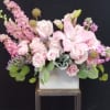 Pink lilies and roses arranged in a white box