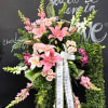 Standing sympathy spray with pink lilies and roses on an easel