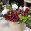 Mixed bouquet of red and white roses with orchids in a beige box