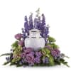 Purple floral arrangement around a white urn
