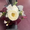 A centerpiece white phalaenopsis orchid, creamy ranunculus blooms, and glossy roses combine