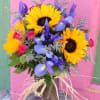 Bouquet of sunflowers, purple irises, and pink roses in a vase