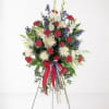 Standing floral spray with red, white, and blue flowers on a wire easel