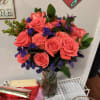 Bouquet of coral roses and purple filler flowers in a glass vase