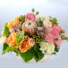 Mixed bouquet of peach, pink, and white flowers in a low white container