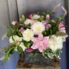 Pink and white floral arrangement in a square glass vase