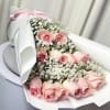 Pink roses with baby's breath in white wrapping and a pink ribbon