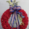 Red floral wreath with blue and white flowers and an American flag ribbon