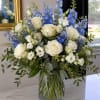 White roses and blue delphinium in a clear glass vase