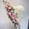 Heart-shaped floral arrangement with pink roses and white flowers on a stand