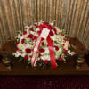 Large red and white floral spray with ribbon on a table