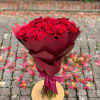Bouquet of red roses wrapped in burgundy paper with a ribbon
