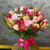 Mixed pink and cream roses in a glass vase with a pink ribbon