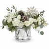 White floral arrangement in a clear glass vase with pinecones and greenery