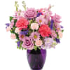 Mixed pink and purple flower arrangement with roses, carnations, and daisies in a deep purple glass vase