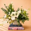 White roses and lilies arranged in a square vase with greenery