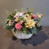 Artificial flower arrangement in a white woven basket with pink and yellow blooms