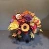 Autumn floral arrangement in a black container with colorful flowers and leaves