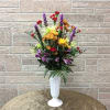 Mixed bouquet in a white pedestal vase with red, purple, and yellow flowers