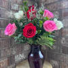 Pink, red, and white roses arranged in a dark glass vase