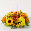 Yellow and orange floral centerpiece with two tall candles