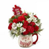 Red and white floral arrangement in a mug with a holiday tag