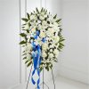 White funeral spray with blue ribbon on a stand